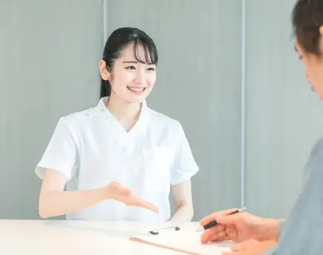 患者様に受付で問診表を記入してもらう虎ノ門ヒルズ龍クリニックのスタッフ