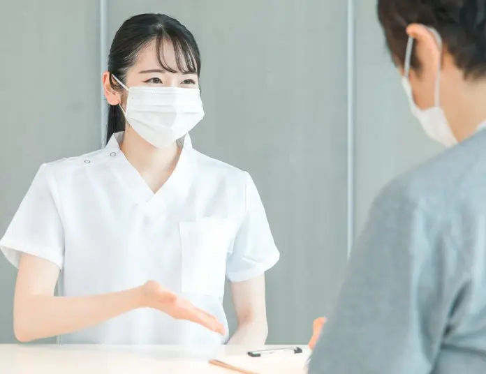 患者さまに寄り添って受付で説明をする虎ノ門ヒルズ龍クリニックのスタッフ